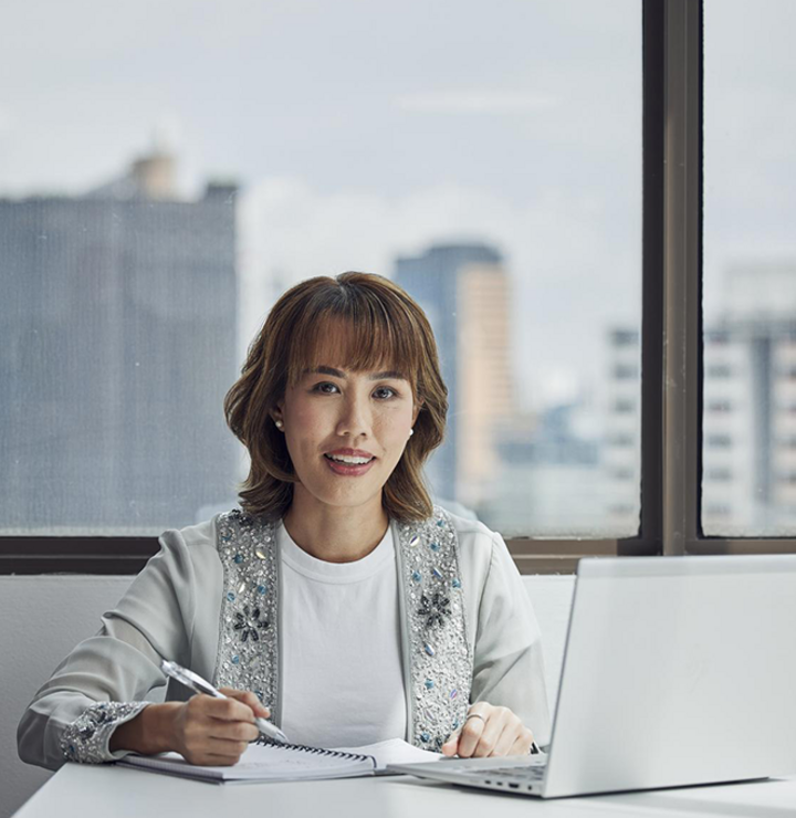 A woman taking notes in front of her laptop sitting in an office