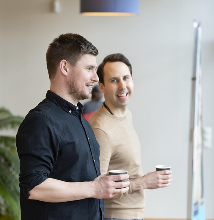 Two men talking and having a coffee looking outside of a window