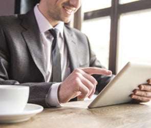 Man in suit reading LinkedIn posts on tablet